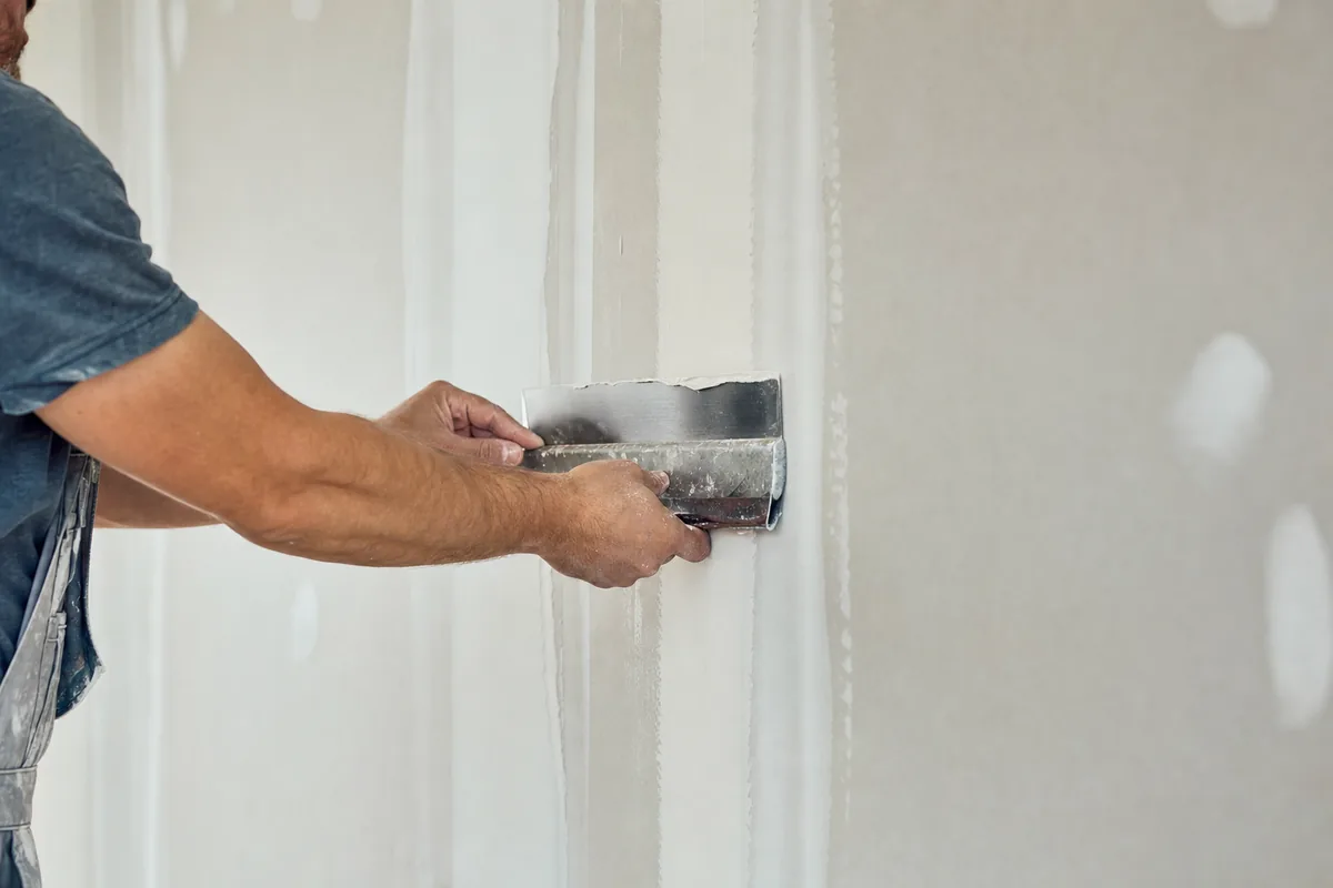 Running a taping knife along a drywall seam